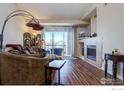 Cozy living room featuring a fireplace, hardwood floors, and sliding glass doors to a balcony at 804 Summer Hawk Dr # 1303, Longmont, CO 80504