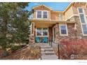 Two-story townhome with stone and siding exterior, front porch, and landscaping at 8399 Flora St # B, Arvada, CO 80005