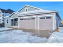 Two-story home with gray siding, three-car garage, and snow-covered driveway at 5753 Pintail Way, Frederick, CO 80504