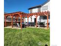 Spacious backyard patio with two wooden pergolas, seating, and a grill at 580 Mount Massive St, Berthoud, CO 80513