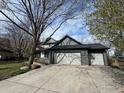 View of the home showcasing its multi-car garage, neutral color palette, and large driveway, complemented by mature trees at 7909 Fairfax Ct, Niwot, CO 80503
