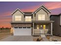 Two-story home with stone accents, an attached two-car garage, and a welcoming front porch at dusk at 399 Blackfoot St, Superior, CO 80027