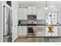 Modern kitchen featuring white cabinets, granite countertops, and stainless steel appliances at 105 Indian Peaks Dr, Erie, CO 80516