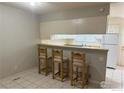 Kitchen features a breakfast bar with three stools and white cabinets at 8266 Washington St # 82, Denver, CO 80229