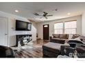 Living room featuring hardwood floors, sectional sofa, and fireplace at 10685 Forester Pl, Longmont, CO 80504