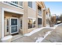 Entrance to a building with a security door and snowy walkway at 1138 Opal St # 101, Broomfield, CO 80020