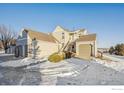 Exterior view of tan condo building with two car garage and snow on the ground at 2141 Sunridge Cir, Broomfield, CO 80020