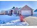 Brick ranch home with attached garage, snowy front yard, and landscaping at 241 Sherwood Ct, Longmont, CO 80504