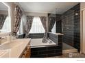 Elegant bathroom with dark tile, a soaking tub, and a glass shower enclosure at 4329 San Marco Dr, Longmont, CO 80503