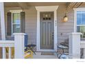 Inviting front porch with seating area and dark gray front door at 462 Canadian Crossing Dr, Longmont, CO 80504