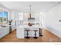 Bright, white kitchen featuring stainless steel appliances, large island, and stylish pendant lighting at 2125 Vine Ave, Boulder, CO 80304