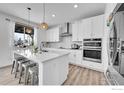 Bright, all-white kitchen with stainless steel appliances, a large island with seating, and modern pendant lighting at 3178 Beaumont Blvd, Mead, CO 80542