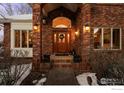 Elegant entryway with a wood door and brick columns at 7172 Waterford Ct, Niwot, CO 80503