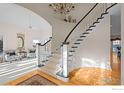 Grand curved staircase with a chandelier and hardwood floors at 7172 Waterford Ct, Niwot, CO 80503