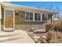 Close-up shot of home's front entrance with well-kept landscaping, brick facade, and a security screen door at 10596 Ura Ln, Northglenn, CO 80234