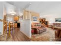 Inviting living room featuring a staircase, comfortable leather furniture, and an open view into the kitchen area at 10596 Ura Ln, Northglenn, CO 80234