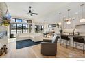 Open living area with white sectional sofa, hardwood floors, and a view of the kitchen at 3364 Danzante Bay Ct, Berthoud, CO 80513