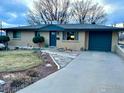 Charming brick home with blue trim, attached garage, and a walkway to the front door under a cloudy sky at 6487 Eaton St, Arvada, CO 80003