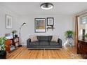 Living room with hardwood floors, gray couch, and wood accent table at 6487 Eaton St, Arvada, CO 80003