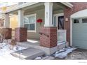 Brick front porch with columns, railing, and snowy steps at 811 Vireo Ct, Longmont, CO 80504