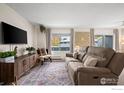 Cozy living room featuring a comfortable couch, stylish TV stand and large windows at 1111 Elysian Field Dr # D, Lafayette, CO 80026