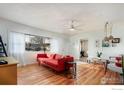 Bright living room featuring hardwood floors, a red couch, and a ceiling fan at 1148 Gay St, Longmont, CO 80501