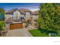 Stunning exterior of a home with a stone facade, wooden garage door, and manicured lawn at 1644 Stardance Cir, Longmont, CO 80504