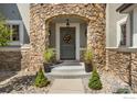 Charming front entrance with stone accents, a wreath, and potted plants at 1644 Stardance Cir, Longmont, CO 80504