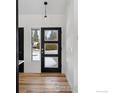 Bright entryway featuring a modern black door with glass panels and hardwood flooring at 4223 Peach Way, Boulder, CO 80301