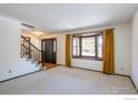 Living room featuring a bay window, neutral carpeting, and staircase at 5580 Colt Dr, Longmont, CO 80503