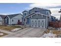 Two-story gray house with white garage doors and blue front door at 605 Wild Honey Dr, Berthoud, CO 80513