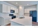 Modern kitchen with white cabinets, island, and black appliances at 6325 Copper Dr, Erie, CO 80516