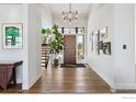 Bright foyer with hardwood floors, modern chandelier, and artistic decor at 635 Paragon Dr, Boulder, CO 80303