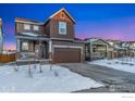 Two-story house with brown siding, attached garage, and snowy front yard at 850 Mosquito Ct, Elizabeth, CO 80107