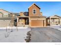 Two-story house with brown and tan siding, attached garage, and snowy front yard at 850 Mosquito Ct, Elizabeth, CO 80107