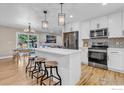 Modern kitchen with stainless steel appliances, quartz countertop island, stylish pendant lights, and an adjacent dining area at 1055 Jade St, Broomfield, CO 80020