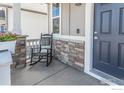 Inviting front porch with a rocking chair and stone accents at 14703 Guernsey Dr, Mead, CO 80542