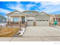 Charming home with a welcoming front porch, three car garage, well-manicured lawn, and beautiful architectural details at 15813 Xanthia Way, Thornton, CO 80602