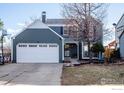 Two-story house with a gray exterior, white garage door, and landscaping at 194 W Sycamore Ln, Louisville, CO 80027