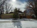 Yellow house with snowy front yard and detached garage at 350 Florence Ave, Firestone, CO 80520