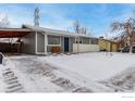 Gray house with a covered carport and snow covered yard at 5332 Granby St, Denver, CO 80239