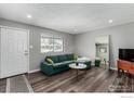 Living room with green couch, wood floors, and a TV at 5332 Granby St, Denver, CO 80239