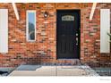 Close-up of a stylish front door with decorative glass and a charming brick facade at 719 Marshall Pl, Berthoud, CO 80513