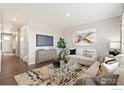 Spacious living room with light beige sofa, large TV, and hardwood floors at 824 Ledge St, Lochbuie, CO 80603