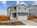 Two-story house with gray and blue siding, white garage door, and a wooden fence at 889 Crest St, Lochbuie, CO 80603