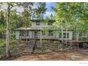 Two-story house with wood deck and stairs, nestled in a wooded area at 11957 Brook Rd, Golden, CO 80403