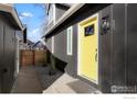 Home entrance with a striking yellow door and well-kept side yard landscaping at 125 Telluride Pl, Longmont, CO 80504