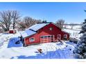 Red barn with a star, surrounded by snow-covered land and outbuildings at 12900 N 66Th St, Longmont, CO 80503