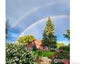 Charming backyard with double rainbow, lush landscaping, and a red barn at 12900 N 66Th St, Longmont, CO 80503