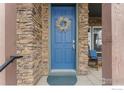 Blue front door with a wreath, stone accents, and wooden posts at 1345 Snowberry Ln, Louisville, CO 80027